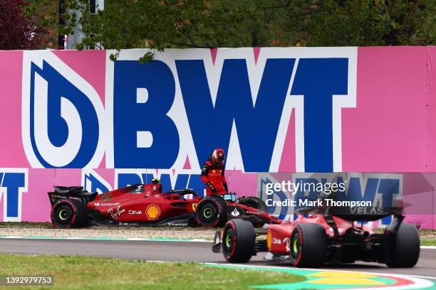 Carlos Sainz of Spain and Ferrari looks on after crashing his car as Charles Leclerc of Monaco driving the Ferrari F1-75 passes him during qualifying...