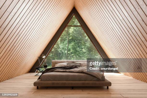 intérieur de petite maison en bois avec meubles de lit et fenêtre triangulaire. - architecture bois photos et images de collection