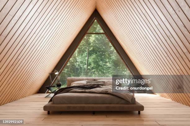 interno della piccola casa in legno con mobili da letto e finestra triangolare. - albergo foto e immagini stock