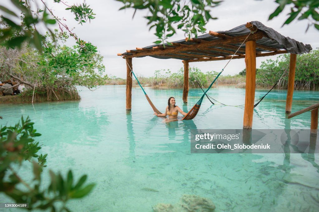 Woman resting in hammock in water in Bacalar Lagoon in Mexico