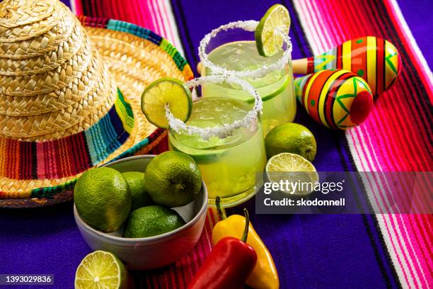 happy cinco de mayo mit zwei margarita-gläsern auf einer bunten mexikanischen decke - hat sombrero stock-fotos und bilder