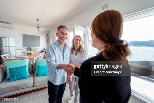 real estate agent showing a mature couple a new house. - waterfront home stock pictures, royalty-free photos & images