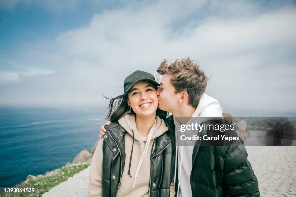 teenager heterosexual couple  kissing outdoors against blue sky - teenage romance stock pictures, royalty-free photos & images