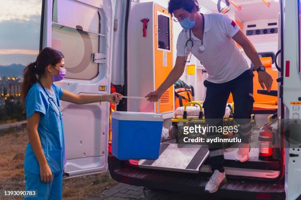 equipo médico en un apuro llevar trasplantes de órganos caja en ambulancia durante la pandemia - transplant surgery fotografías e imágenes de stock