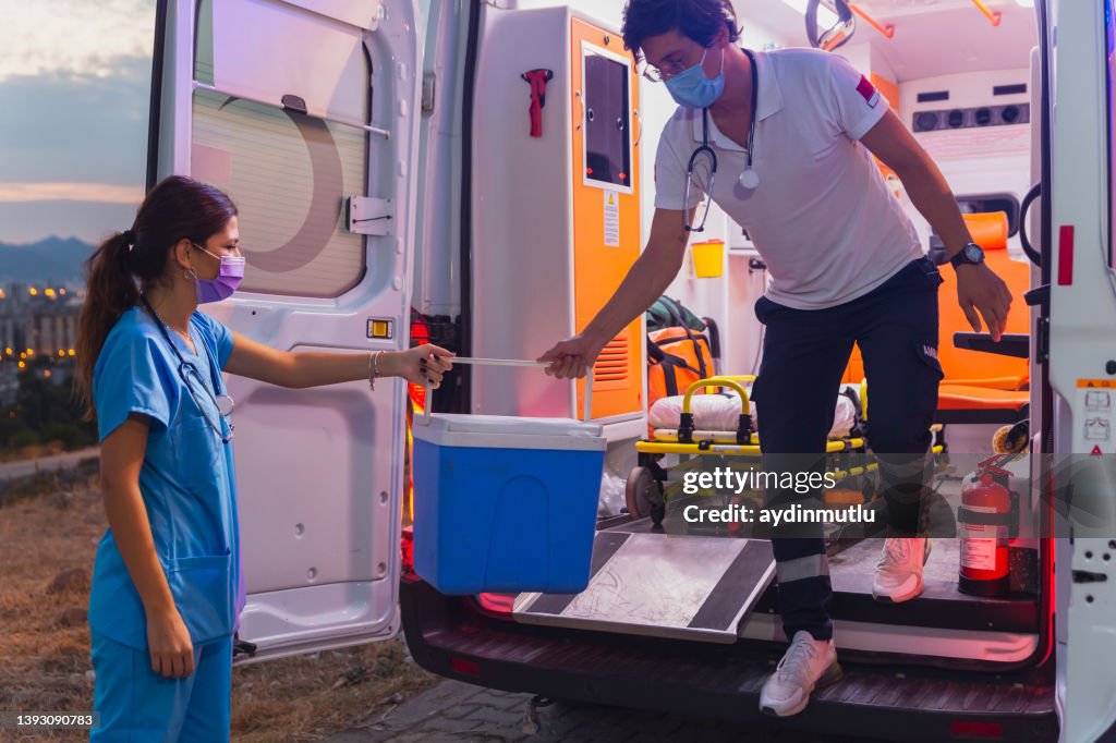 Medical team in a hurry carrying organ transplants box by ambulance during pandemic