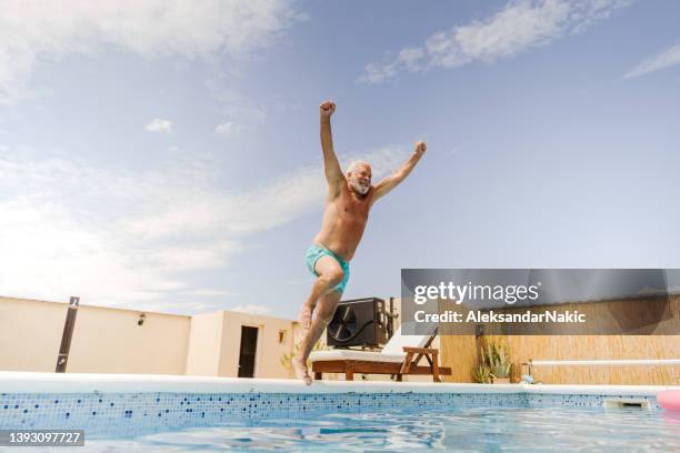 senior man jumping into the swimming pool - jump in pool stock pictures, royalty-free photos & images