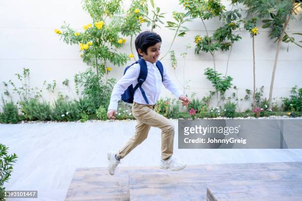 active young middle eastern boy returning home from school - khaki trousers stockfoto's en -beelden