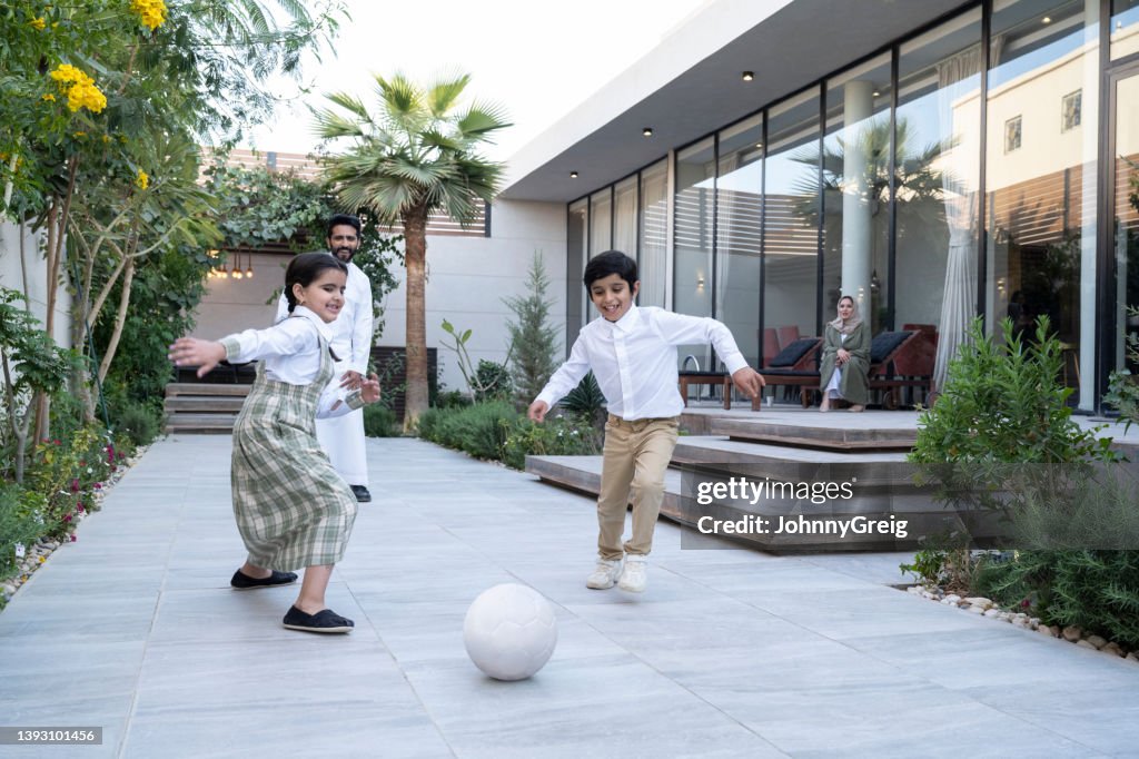 Saudi father playing football with children at home