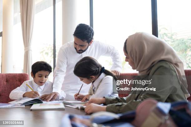 saudische familie mit zwei kindern, die zusammen hausaufgaben machen - young girls homework stock-fotos und bilder