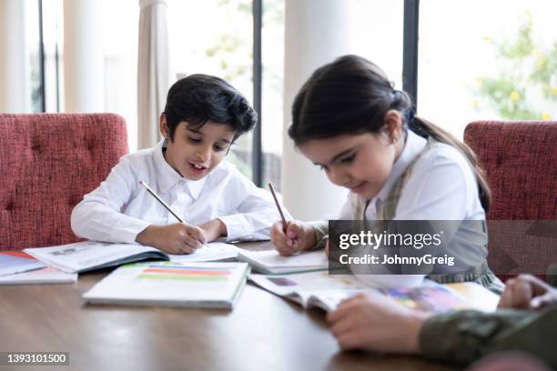 de jeunes écoliers saoudiens font leurs devoirs à table à manger - arab student kids photos et images de collection