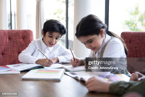 young saudi schoolchildren doing homework at dining table - saudi kids stock pictures, royalty-free photos & images