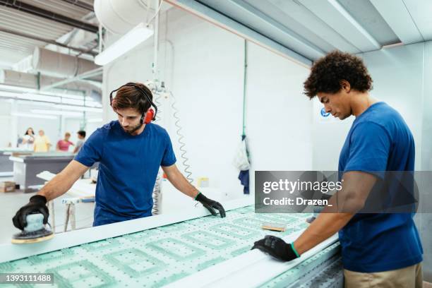 diverse manual workers sanding wooden planks on production line - trabajador manual stock pictures, royalty-free photos & images