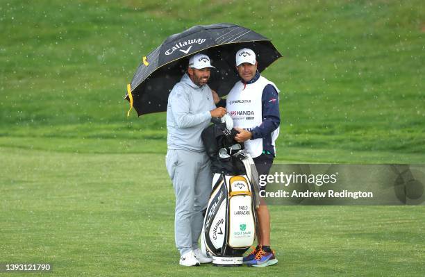 Pablo Larrazabal of Spain and his caddie take shelter on the second hole as hailstones and bad weather stop play during Day Three of the ISPS Handa...