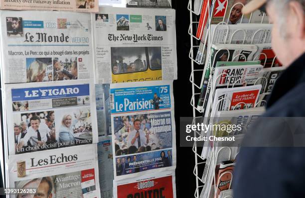 Man looks at the front pages of the French newspapers, Le Monde, Le Figaro, Les Echos, Le Parisien and Liberation displayed with the photos of...