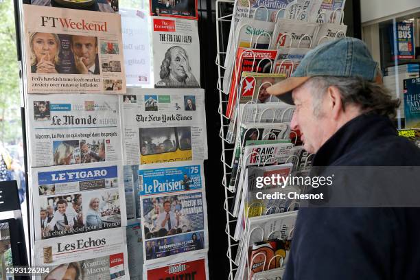 Man looks at the front pages of the French newspapers, le Monde, Le Figaro, Les Echos, Le Parisien and Liberation displayed with the photos of...
