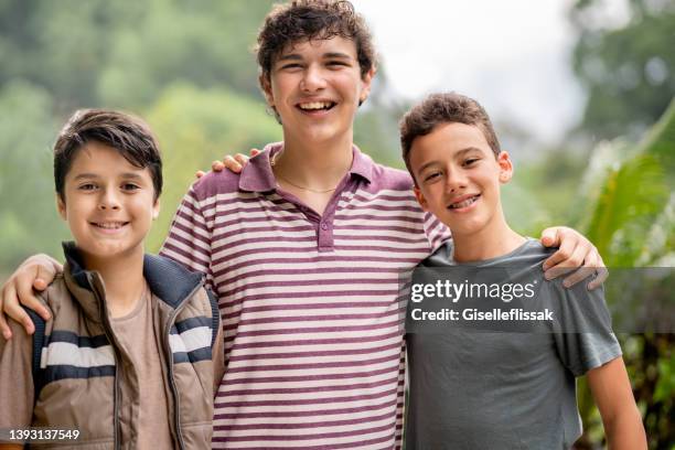 lächelnde teenager-freunde, die im sommer zusammen draußen stehen - teens brothers stock-fotos und bilder