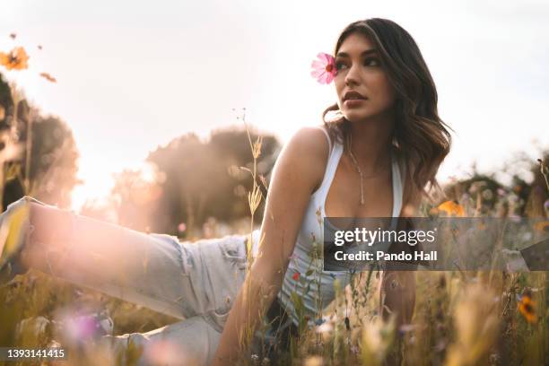 beautiful brunette young woman with a pink flower behind her ear - adorno floral fotografías e imágenes de stock