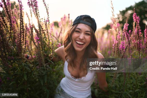 beautiful brunette young woman smiling in front of huge pink flowers - beautiful woman laughing stock-fotos und bilder