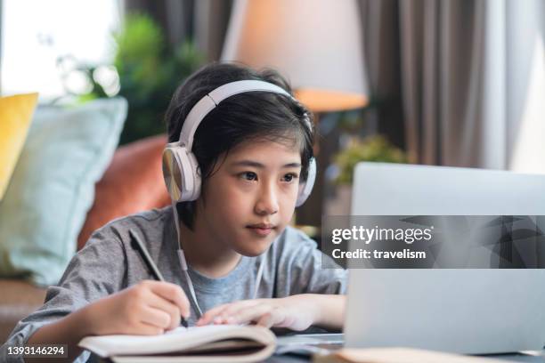 asaian child boy kid  taking an e-learning learning online class from school teacher by digital remote device laptop internet meeting in living room ,asia teen wear headphone using laptop e learning class at home - boy thailand stock pictures, royalty-free photos & images