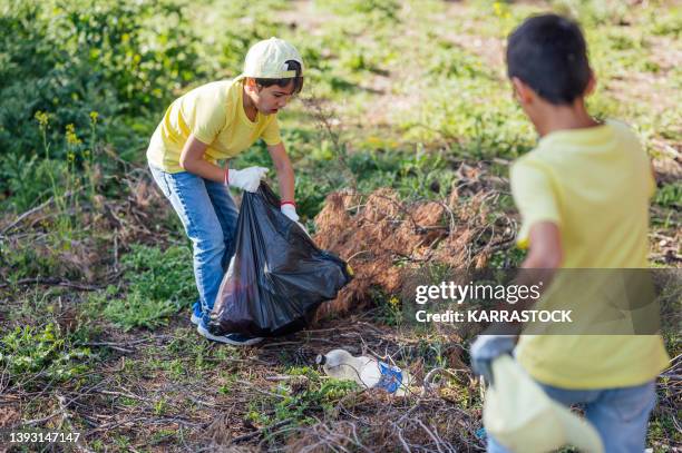 group of volunteering children collecting garbage in a park. - land clearing stock pictures, royalty-free photos & images