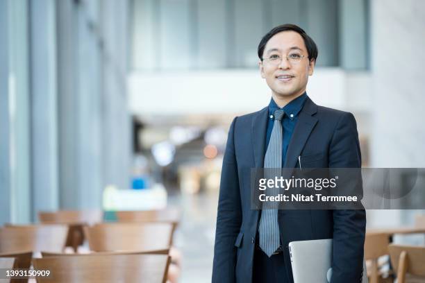 adaptability is the key to business growth. a senior japanese business owner holding laptop and stading in convention centre during product launch into the competitive market. - ceo ストックフォトと画像