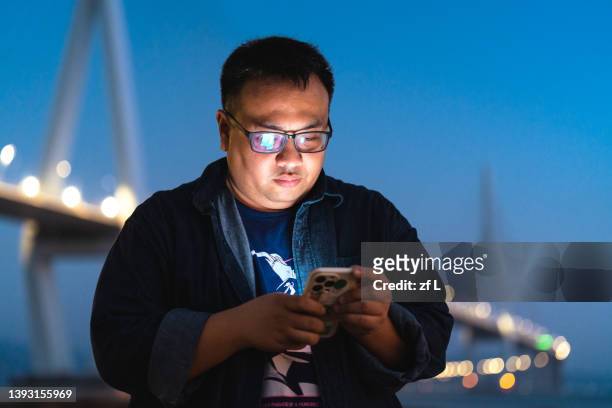 look at mobile phones, young confident overweight men - fat asian man stockfoto's en -beelden