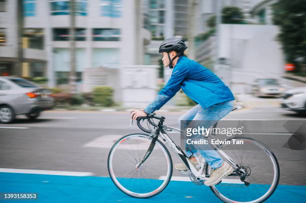 asiatischer chinese, der in der stadt auf dem fahrradweg zur arbeit radelt, nachhaltiger lebensstil - bicycle lane stock-fotos und bilder