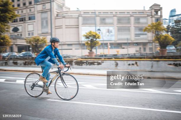 asiatischer chinese, der in der stadt auf dem fahrradweg zur arbeit radelt, nachhaltiger lebensstil - bicycle lane stock-fotos und bilder