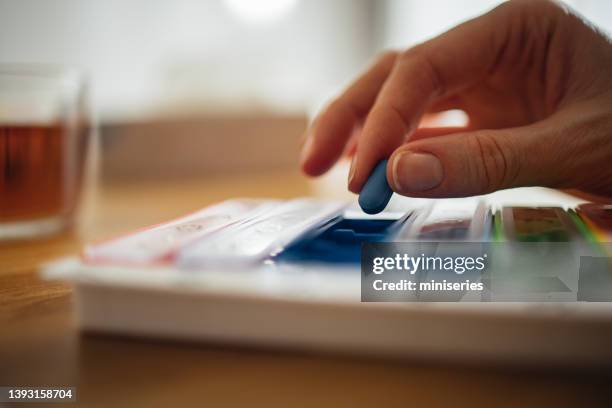 unkenntliche frau, die medikamente aus der pillen-organizer-box zu hause einnimmt - tablettenschachtel stock-fotos und bilder