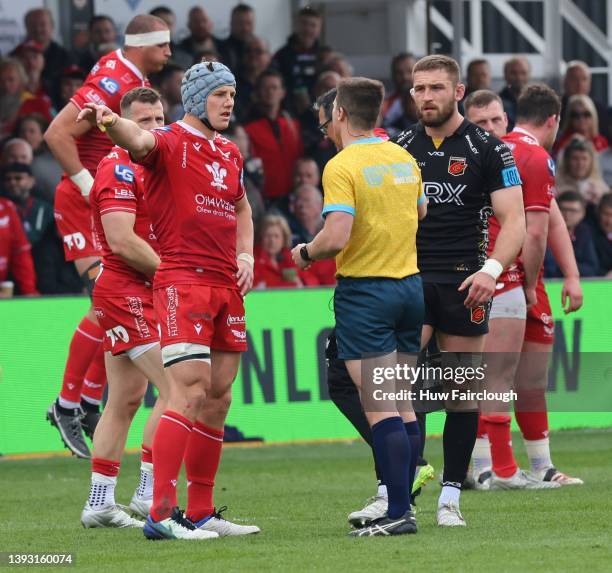 Jonathan Davies of the Scarlets and Harri Keddie of the Dragons are spoken to by the match official during the the United Rugby Championship match...