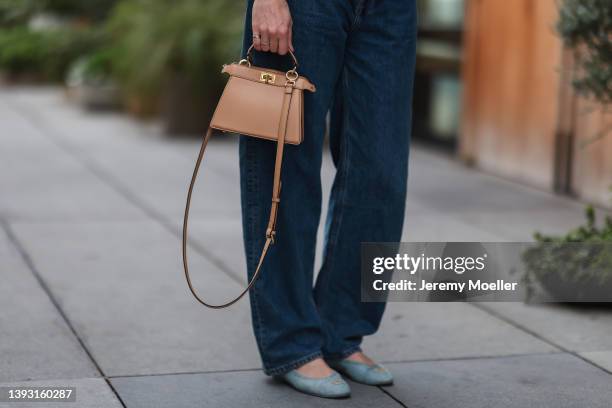 Veronika Heilbrunner seen wearing a light brown Fendi Peekaboo bag, a dark blue denim jeans from Calvin Klein x Palace and light blue denim sandals...