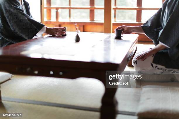 two people in yukata "japanese onsen robe" drinking a green tea  in tatami mat room - washitsu stock pictures, royalty-free photos & images