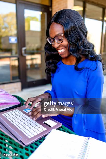 happy teacher using device outside - administrative professionals day stock-fotos und bilder