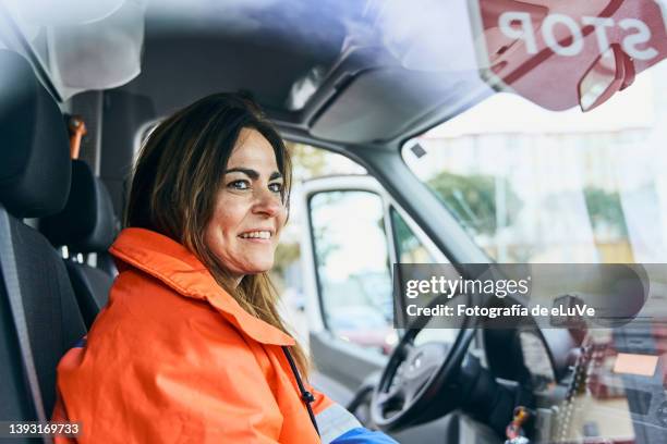 woman paramedic smoking to coworker seen through ambulance windshield - paramedics stock-fotos und bilder