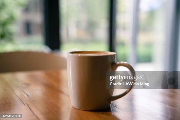 a cup of coffee on a wooden table - マグカップ ストックフォトと画像