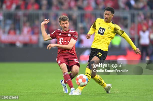 Thomas Mueller of FC Bayern Muenchen is challenged by Jude Bellingham of Borussia Dortmund during the Bundesliga match between FC Bayern Muenchen and...