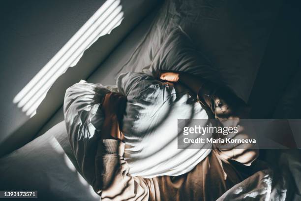 woman suffering from depression. 
woman covering her face with pillow. - insomnia foto e immagini stock