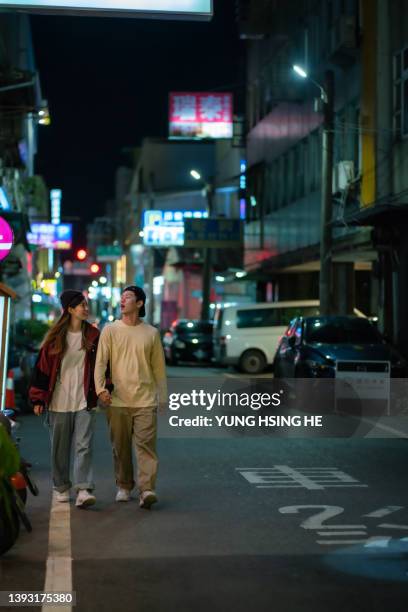 asia, a taiwanese couple walking and chatting on the street at night. - taiwan night market stock pictures, royalty-free photos & images