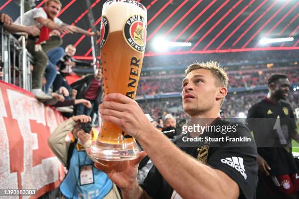 Joshua Kimmich of FC Bayern Muenchen celebrates with the fans by handing a beer over during the Bundesliga match between FC Bayern Muenchen and...