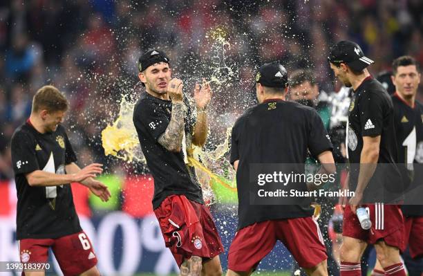 Lucas Hernandez of FC Bayern Muenchen is showered in beer after their sides victory during the Bundesliga match between FC Bayern Muenchen and...