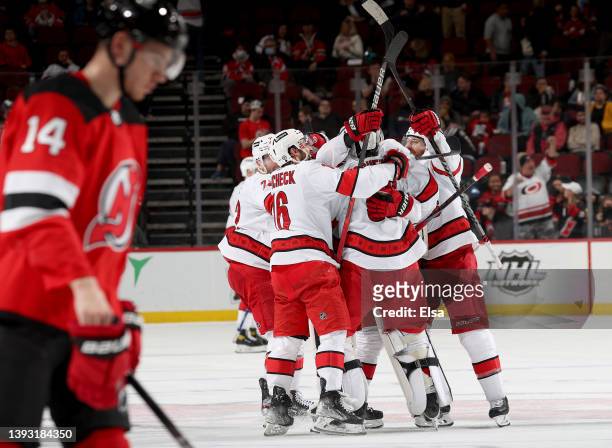 Pyotr Kochetkov of the Carolina Hurricanes celebrates with teammates after the win as Nathan Bastian of the New Jersey Devils skates off the ice at...
