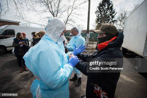 Volunteer dons protective gear before moving body bags, as a Ukrainian morgue overflows with victims who died during the Russian military presence in...