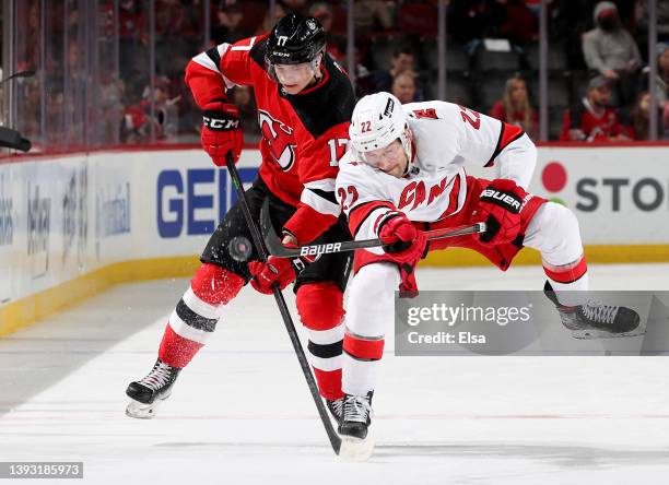 Brett Pesce of the Carolina Hurricanes passes the puck as Yegor Sharangovich of the New Jersey Devils defends during the third period at Prudential...