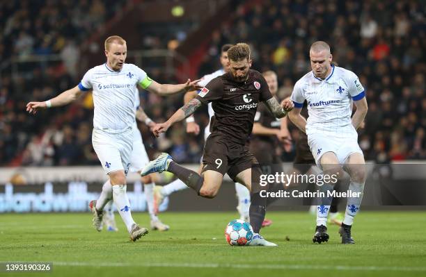 Guido Burgstaller of FC St. Pauli is challenged by Fabian Holland and Thomas Isherwood of SV Darmstadt 98 during the Second Bundesliga match between...