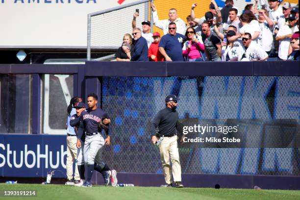 Oscar Mercado of the Cleveland Guardians is restrained as fans throw debris on the field following Gleyber Torres of the New York Yankees walk off...