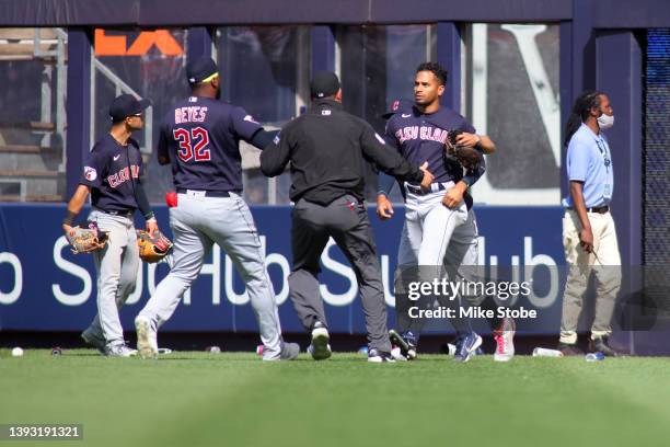 Oscar Mercado of the Cleveland Guardians is restrained as fans throw debris on the field following Gleyber Torres of the New York Yankees walk off...