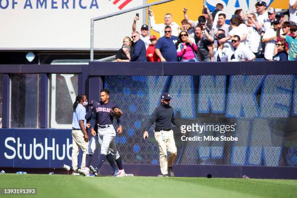 Oscar Mercado of the Cleveland Guardians is restrained as fans throw debris on the field following Gleyber Torres of the New York Yankees walk off...