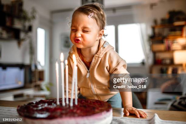 little birthday girl blowing out candles on cake at home - barnkalas bildbanksfoton och bilder