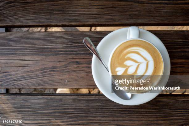 cappuccino on top with heart flower latte art lay on wooden outdoor bench. - capuccino fotografías e imágenes de stock
