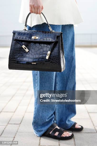 Influencer Maria Barteczko wearing a black lock bag by Picard and black fur sandals by Hermes during a street style shooting on April 23, 2022 in...